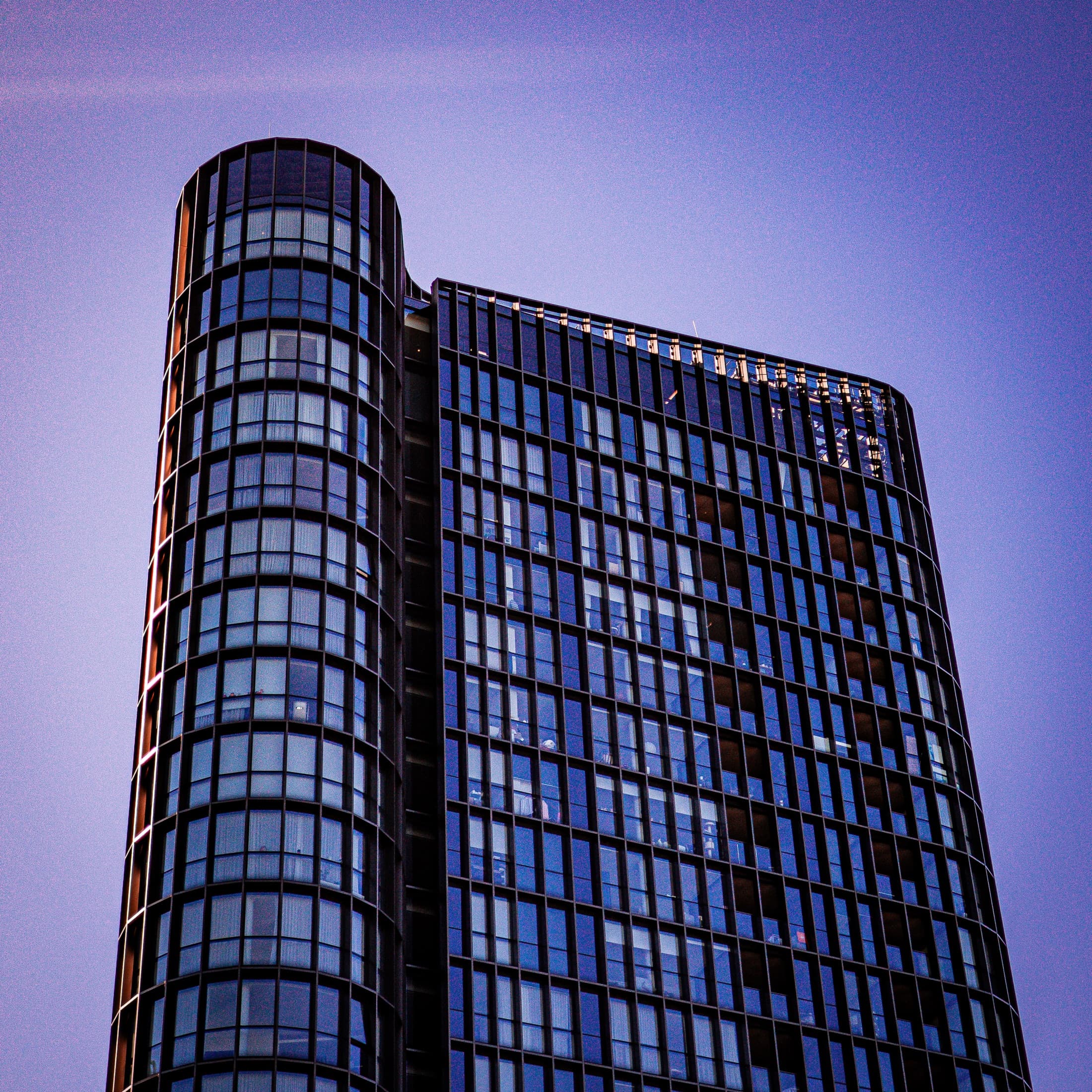 Curved glass tower against a violet sky